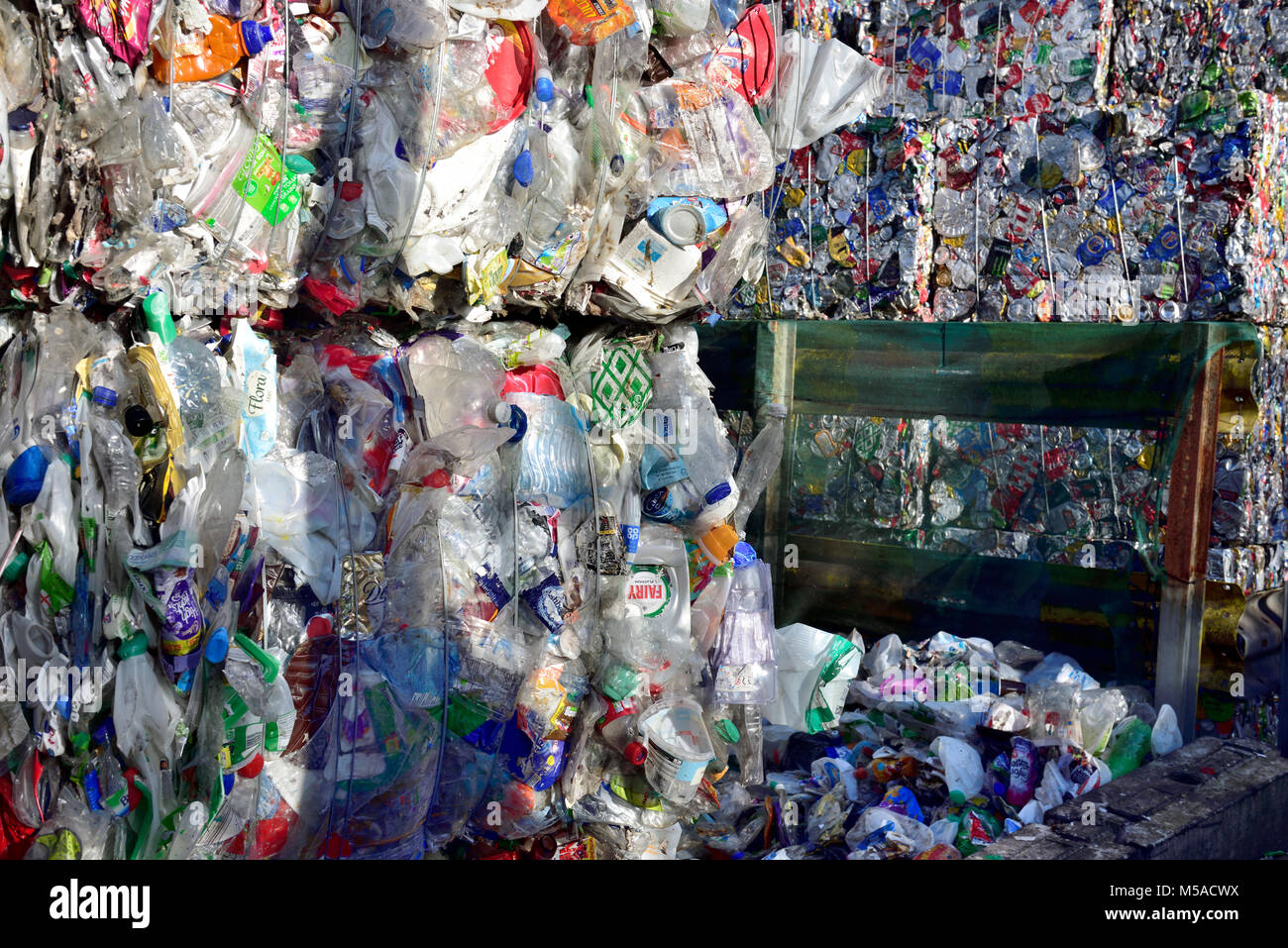 Post consumer waste plastic bottles and cans compressed into bails and stacked at recycling plant Stock Photo