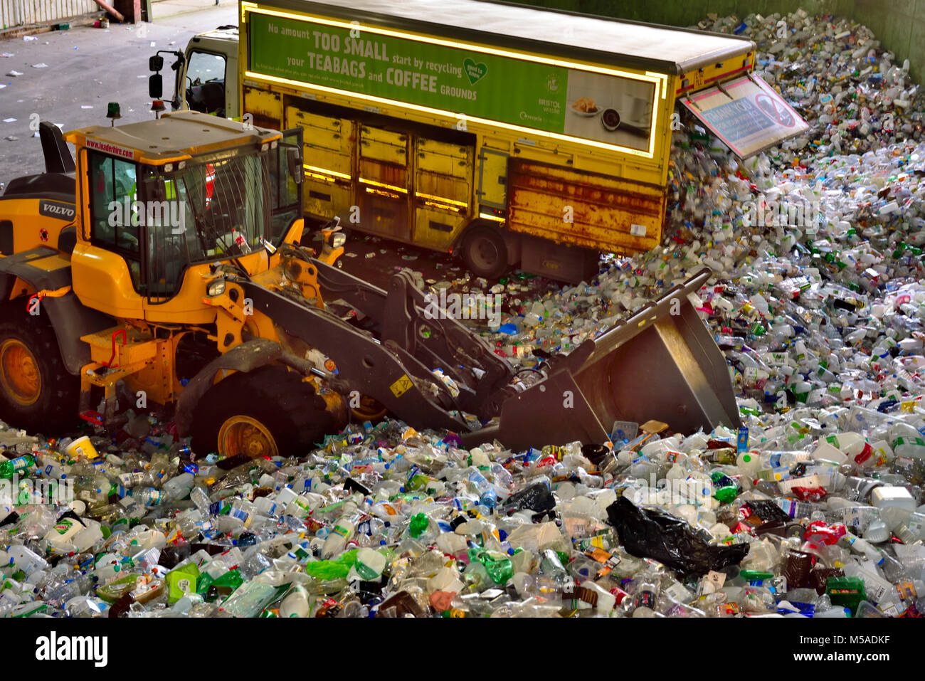 Post consumer waste, plastic bottles and tins, brought into recycling plant by collection lorry being moved by tractor for sorting, UK Stock Photo