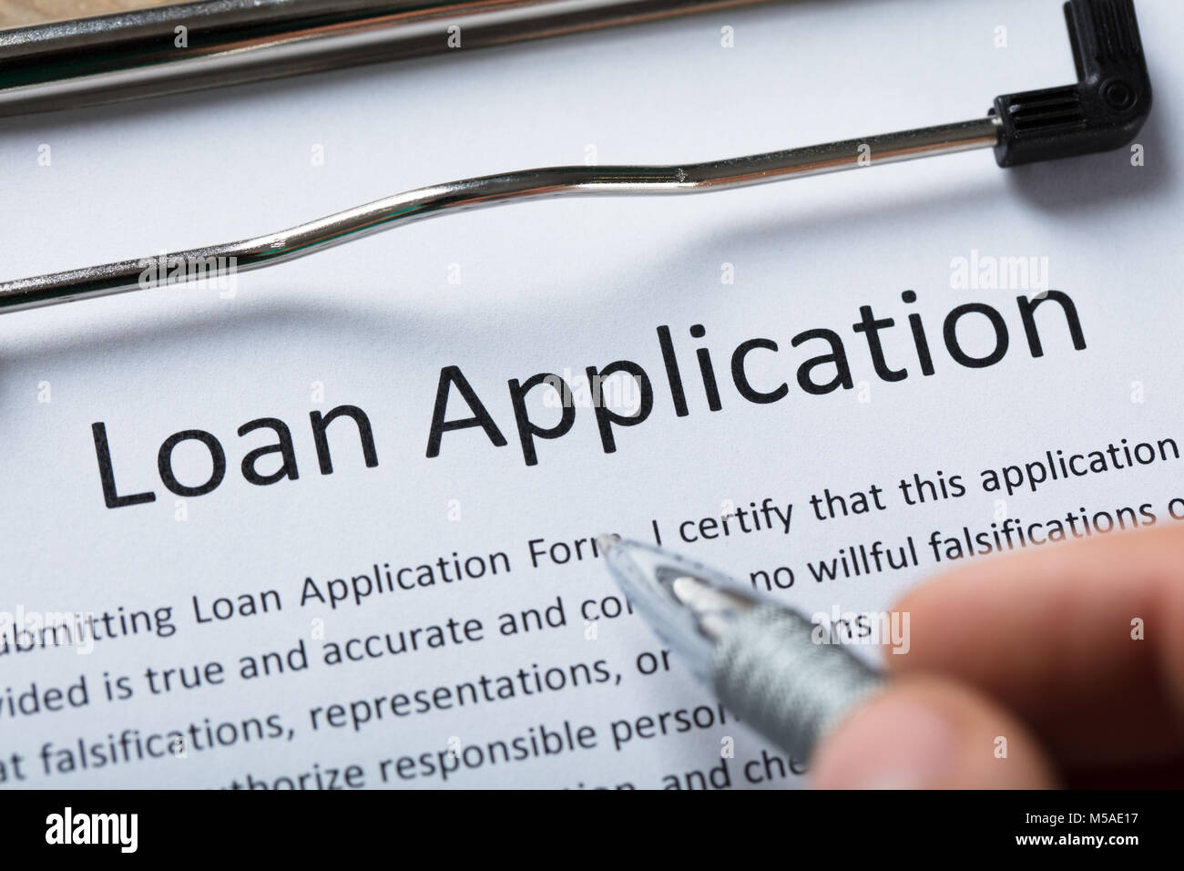 Close-up Of A Person's Finger With Pen Over Loan Application Form Stock Photo