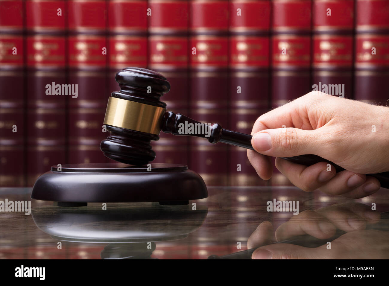 Close-up Of A Person's Hand Striking Gavel On Sounding Block In Courtroom Stock Photo
