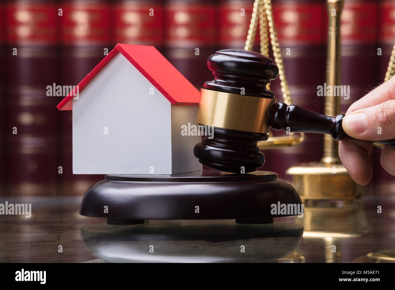 Close-up Of A Person Striking Mallet With House Model On Sounding Block Stock Photo