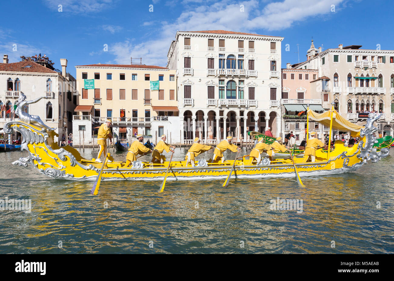 Historic boats in the Regata Storica, Grand Canal, Venice, Italy with rowers in a bright yellow boat with matching costumes carrying a dignatory Stock Photo