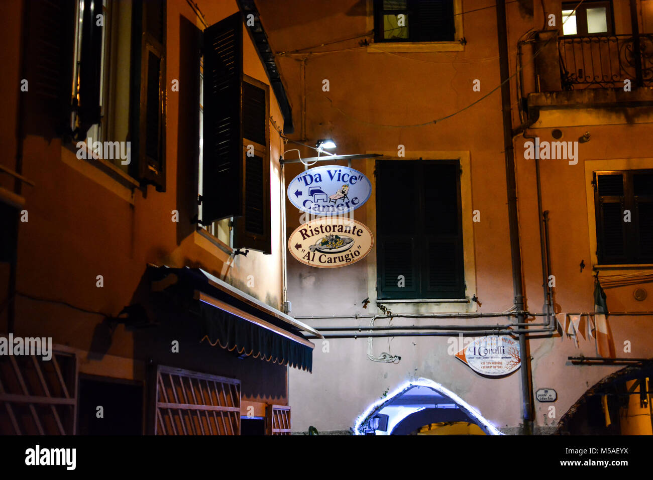 Late night in Monterosso Al Mare, Cinque Terre Italy with a colorful sign of violet and peach advertising an Italian restaurant and rooms for rent Stock Photo