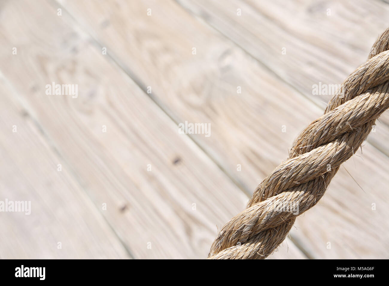 Aged rope with wooden floor boards in the background creating a natural ...