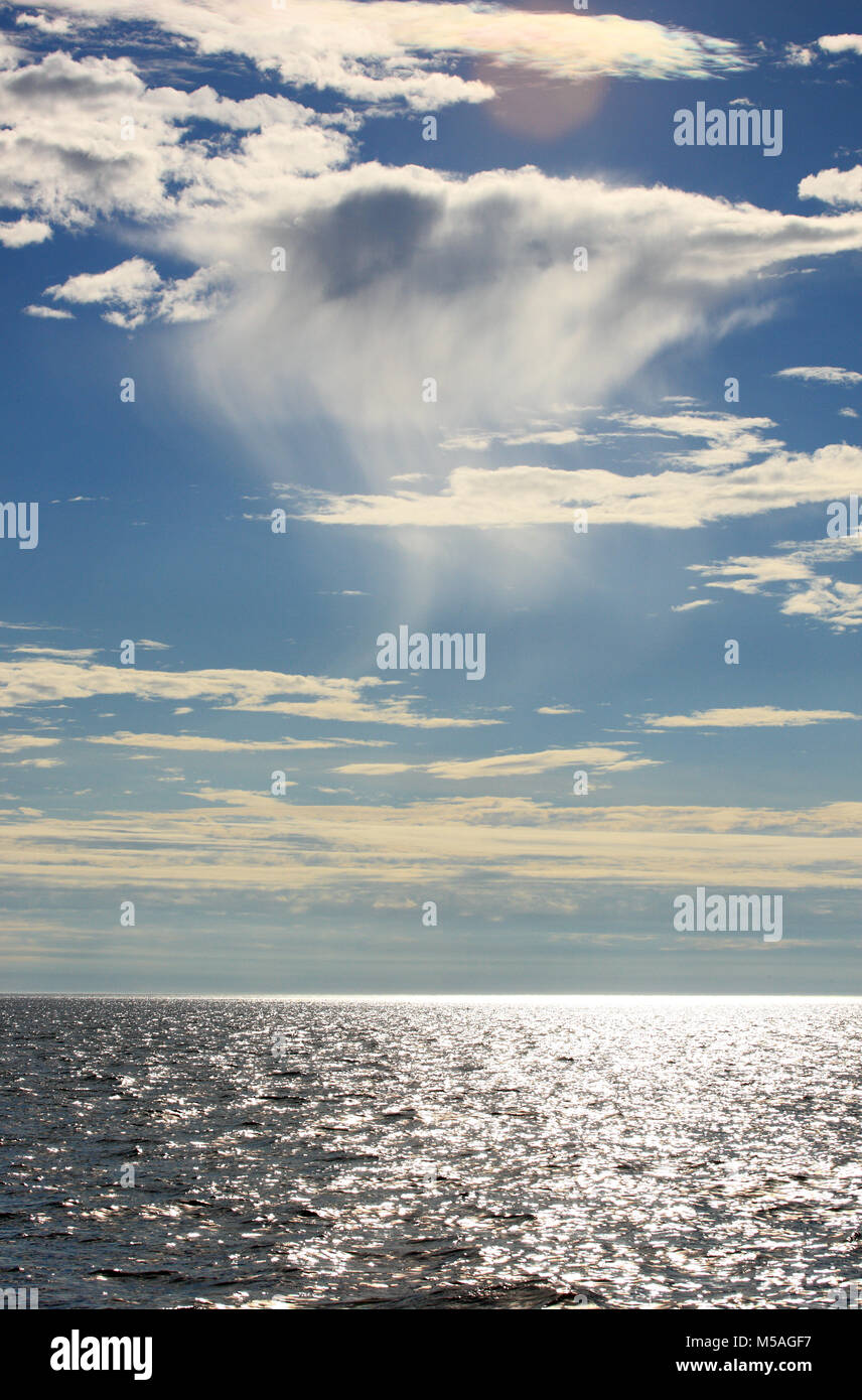 Late afternoon sunshine filtering through wispy clouds and sparkling in the sea Stock Photo