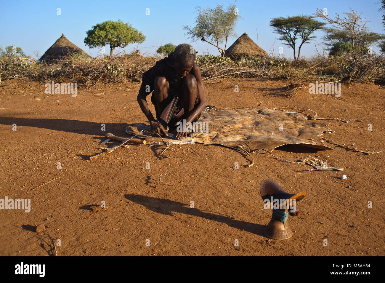 A man is tanning leather ( Ethiopia). He belongs to the Hamer tribe. Stock Photo