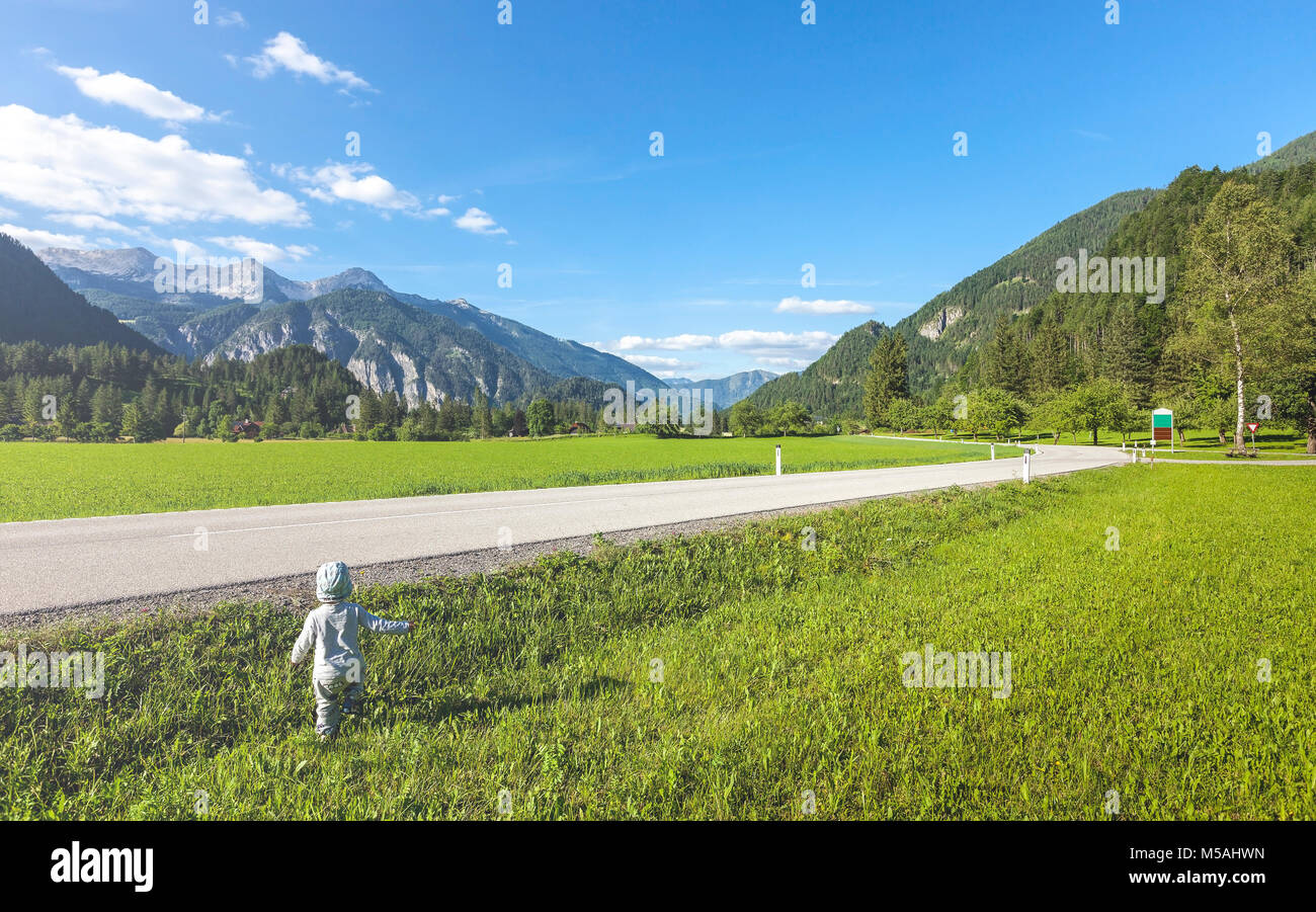 Little boy beside street surrounded by landscape and mountains Stock Photo