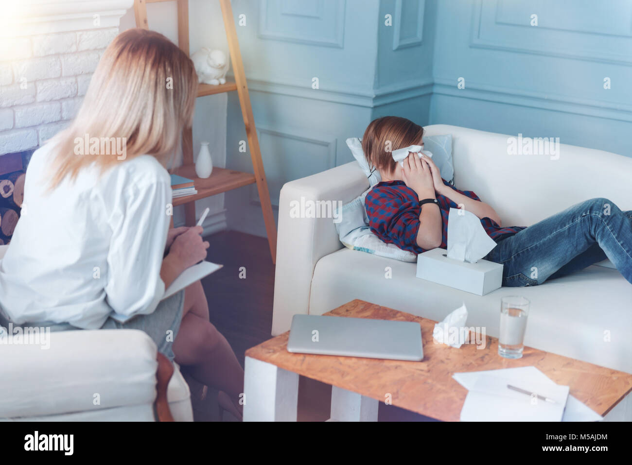 Scared child crying while talking with psychotherapist Stock Photo