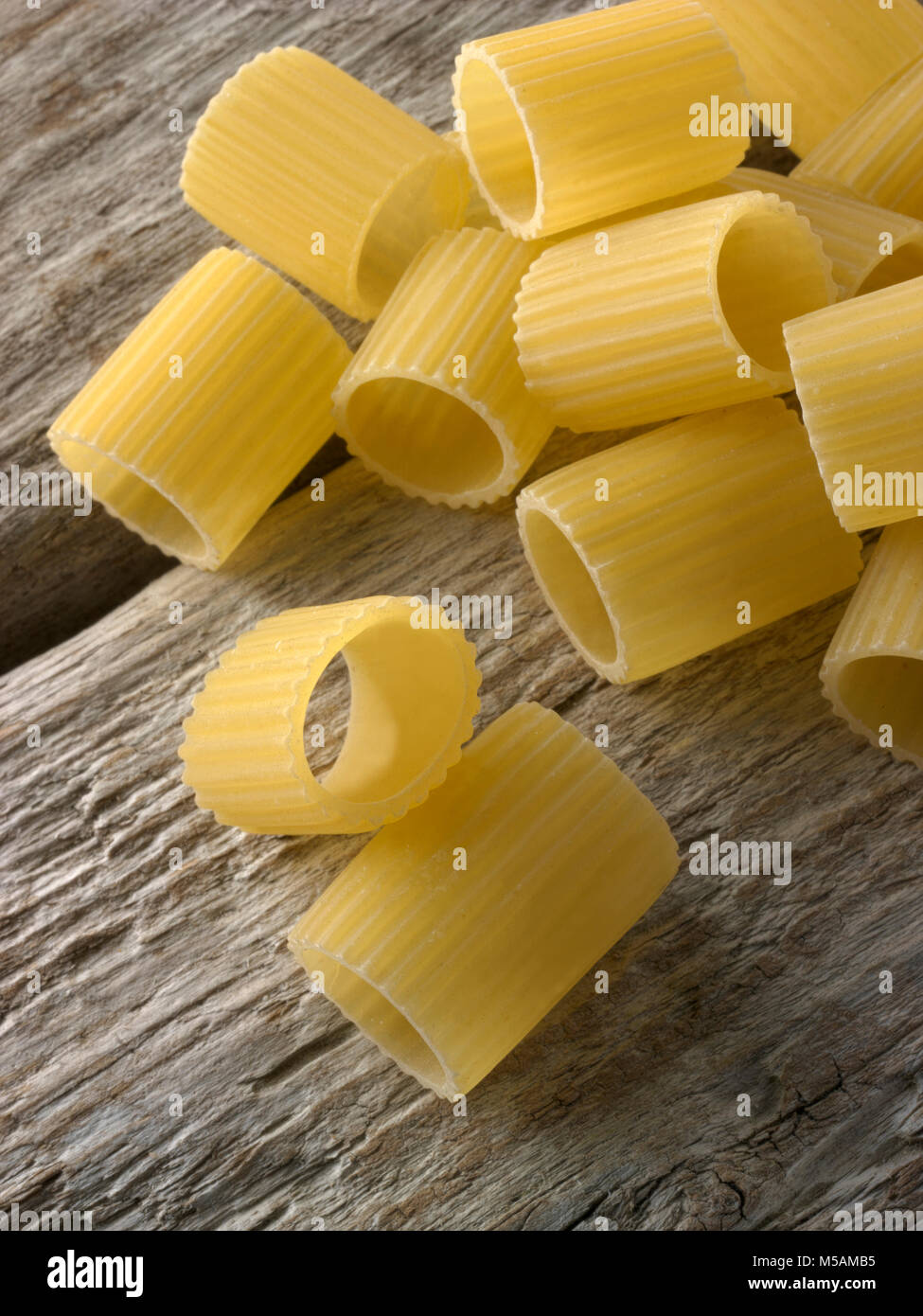 Traditional dried  Italaian Mezze Maniche Rigate pasta close up in a rustic setting on wood Stock Photo