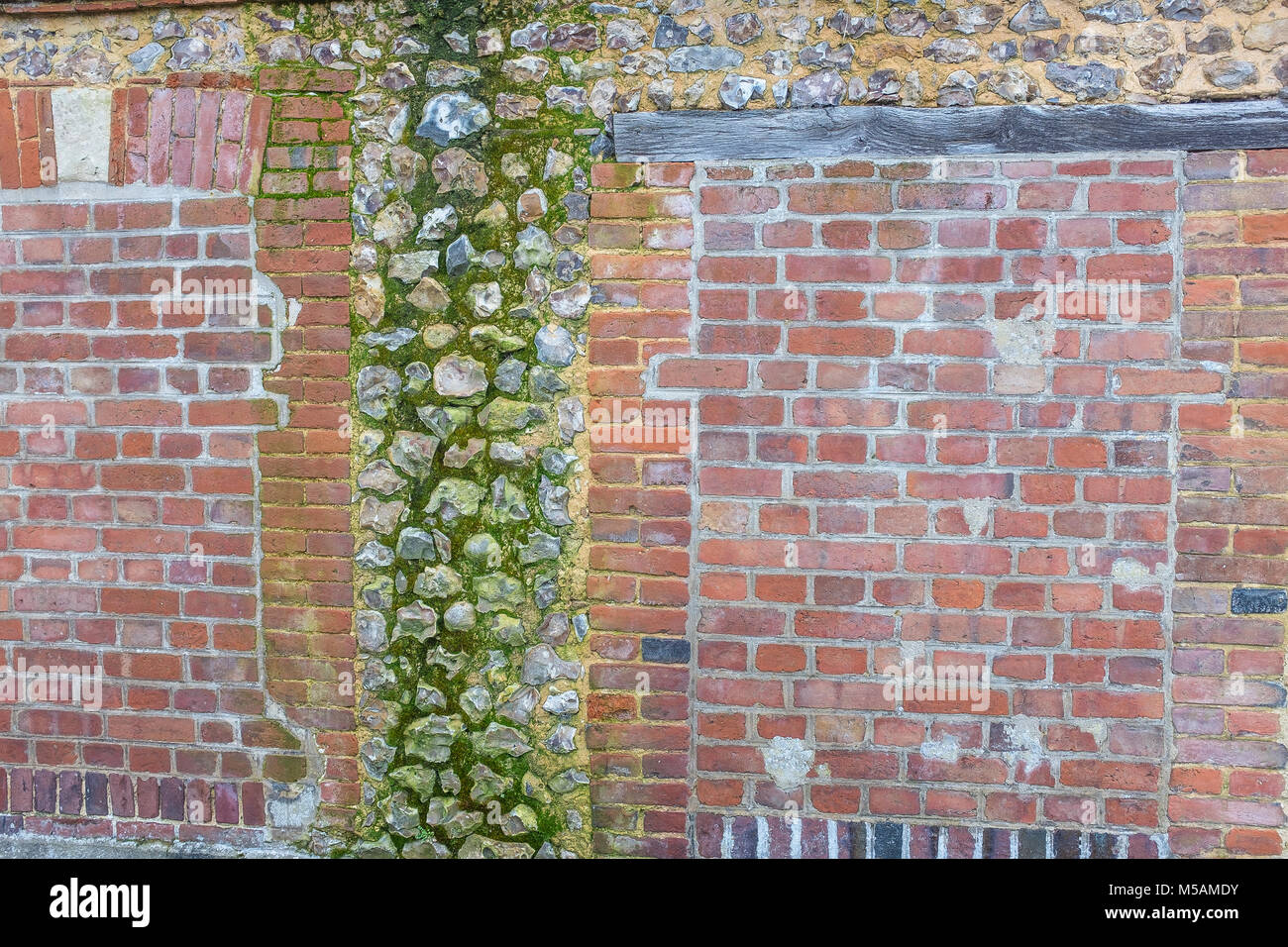 Panoramic image of Decorativeold flint, red brick, wall with green and yellow vegetable moss Stock Photo