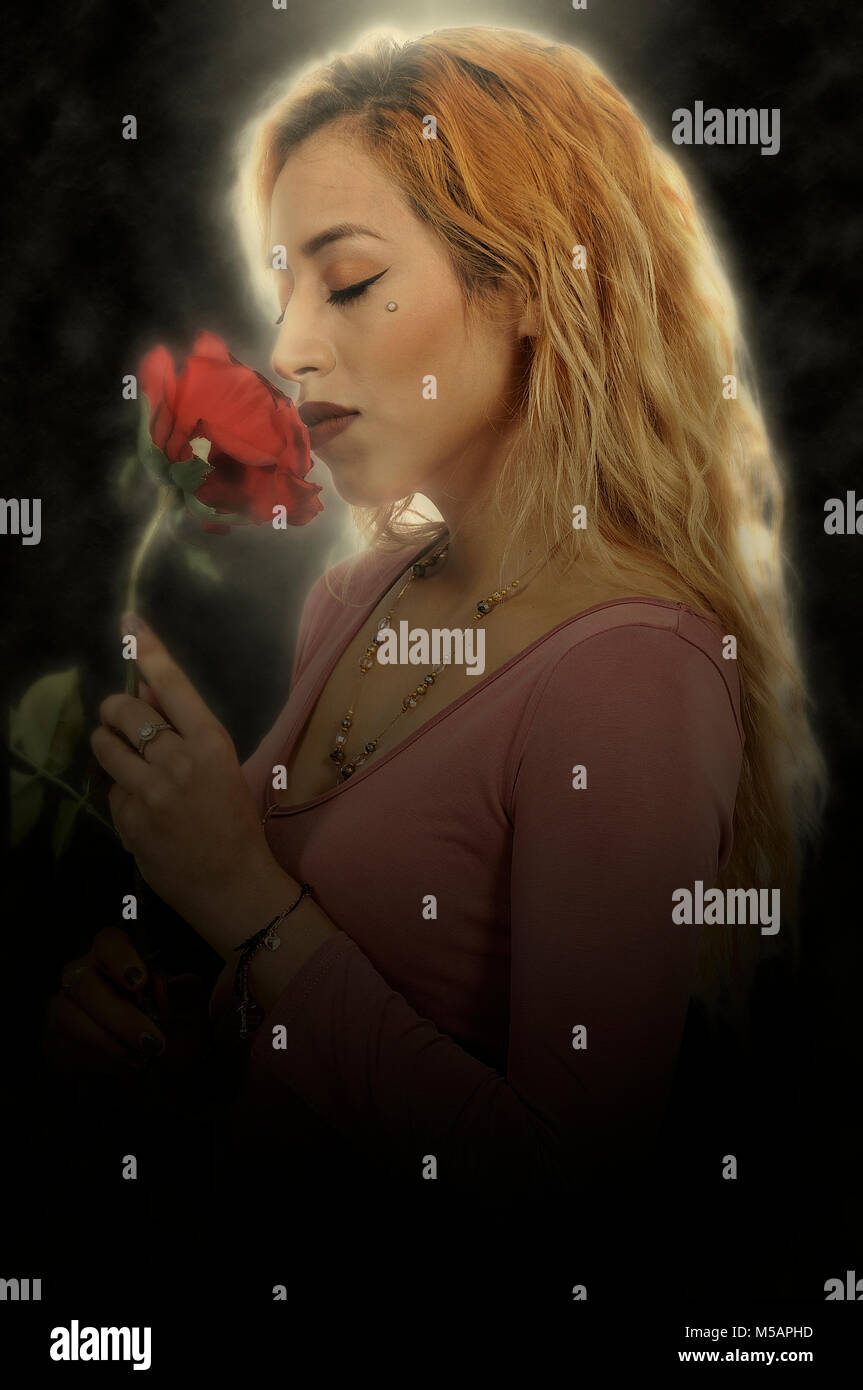 Beautiful woman smelling a fresh cut rose Stock Photo - Alamy