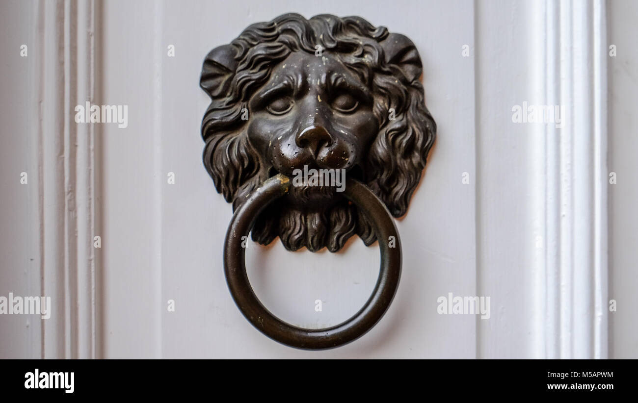 Ancient dark Doorknob in the shape of a Lion at white door Stock Photo