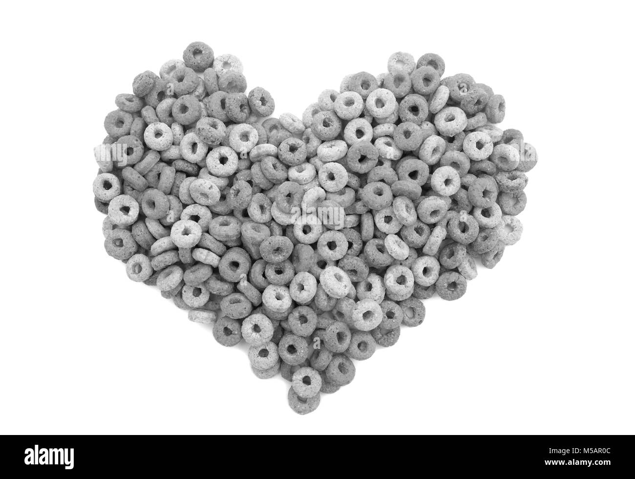 Multigrain hoops breakfast cereal - wheat, barley, rice, oats and maize - in a heart shape, isolated on a white background - monochrome processing Stock Photo