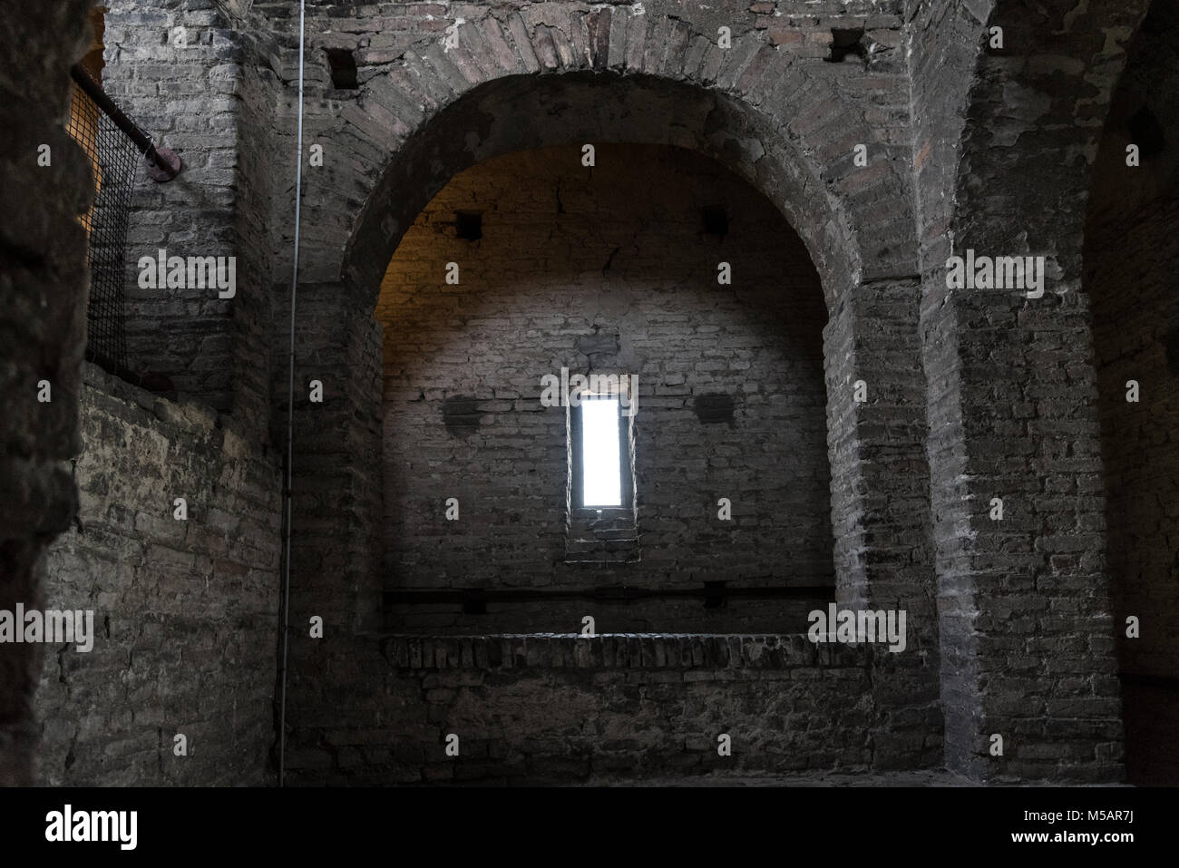 Stone interior with window of an old steeple crypt, located inside an ancient catholic church Stock Photo