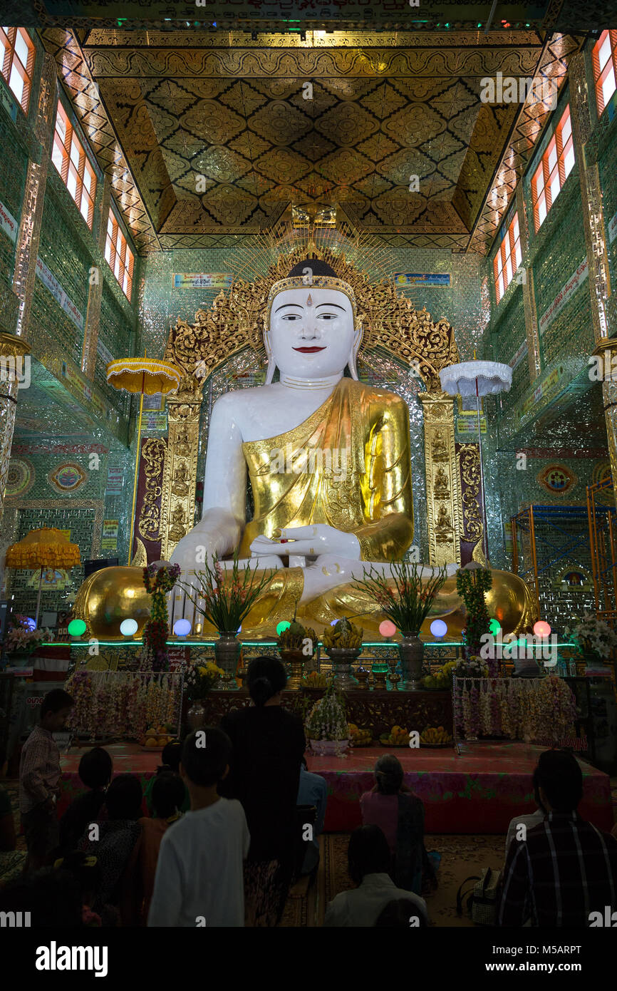 People in front of a tall statue of sitting Buddha at the Soon U Ponya Shin Pagoda on the Sagaing Hill in Mandalay, Myanmar (Burma). Stock Photo