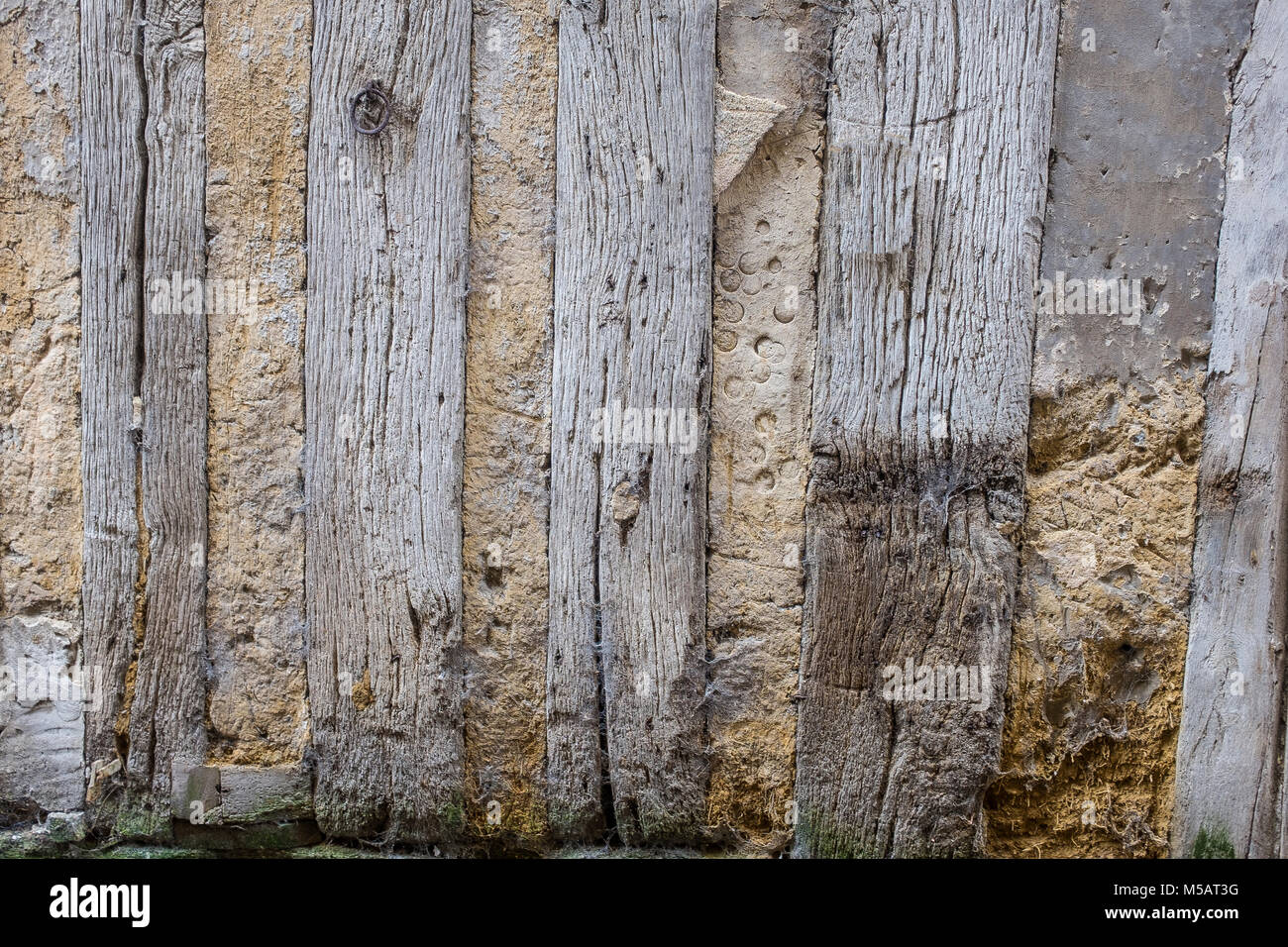 Detail of an old half-timbered house with dirty walls and weathered wood,damaged, , damaged, at the bottom of the wall, with green moss,abstact photo France, Normandy. Stock Photo