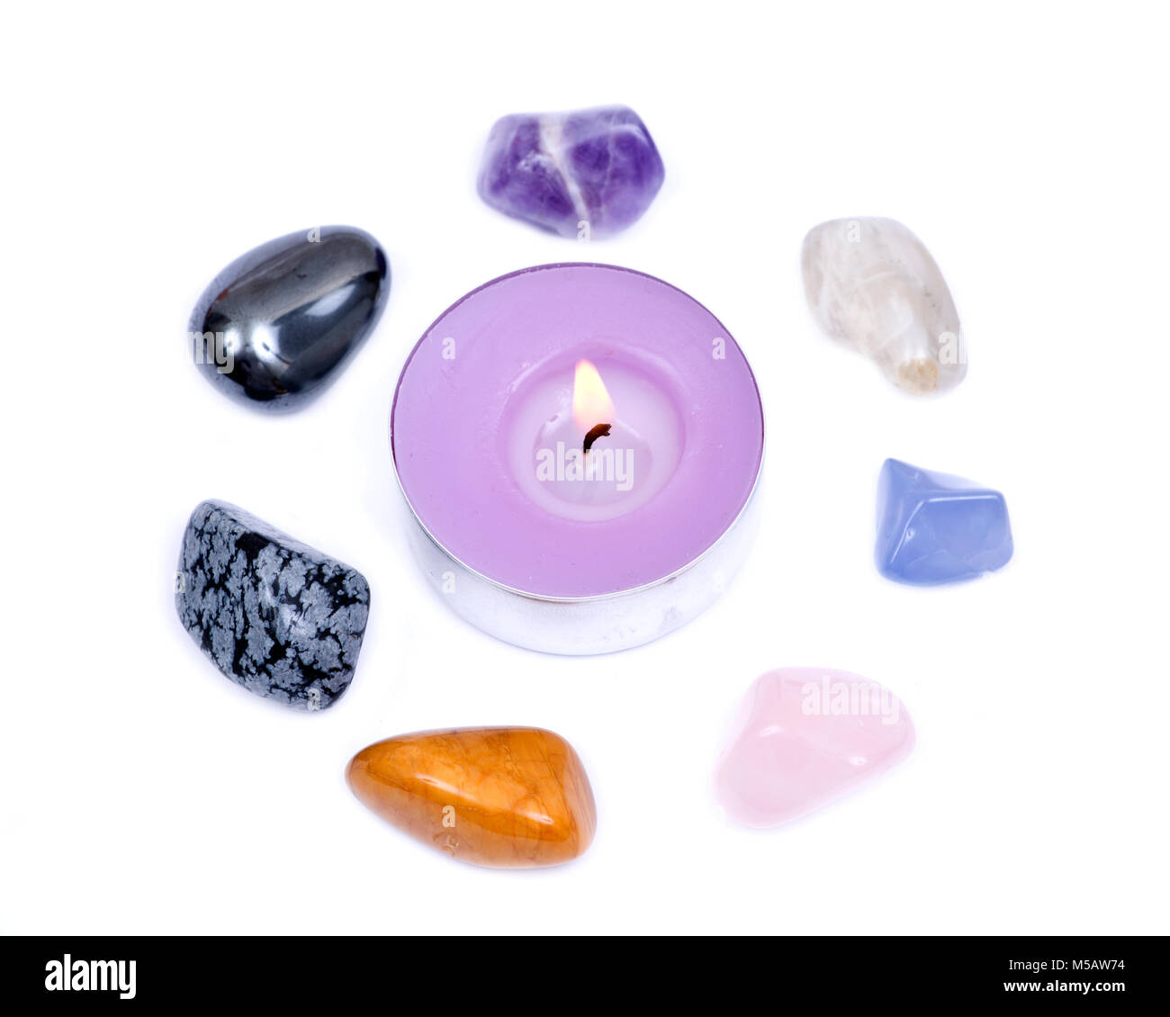 Lavender tea light candle surrounded by set of seven healing chakra