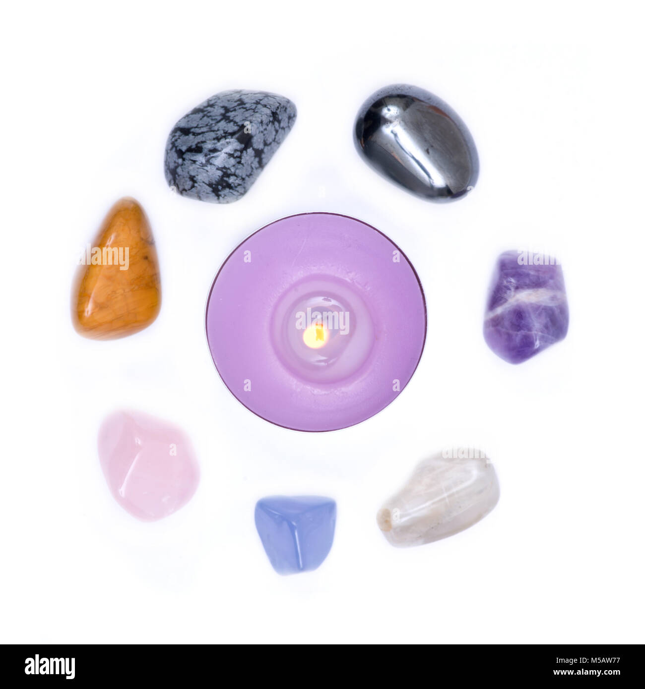 Lavender tea light candle surrounded by set of seven healing chakra