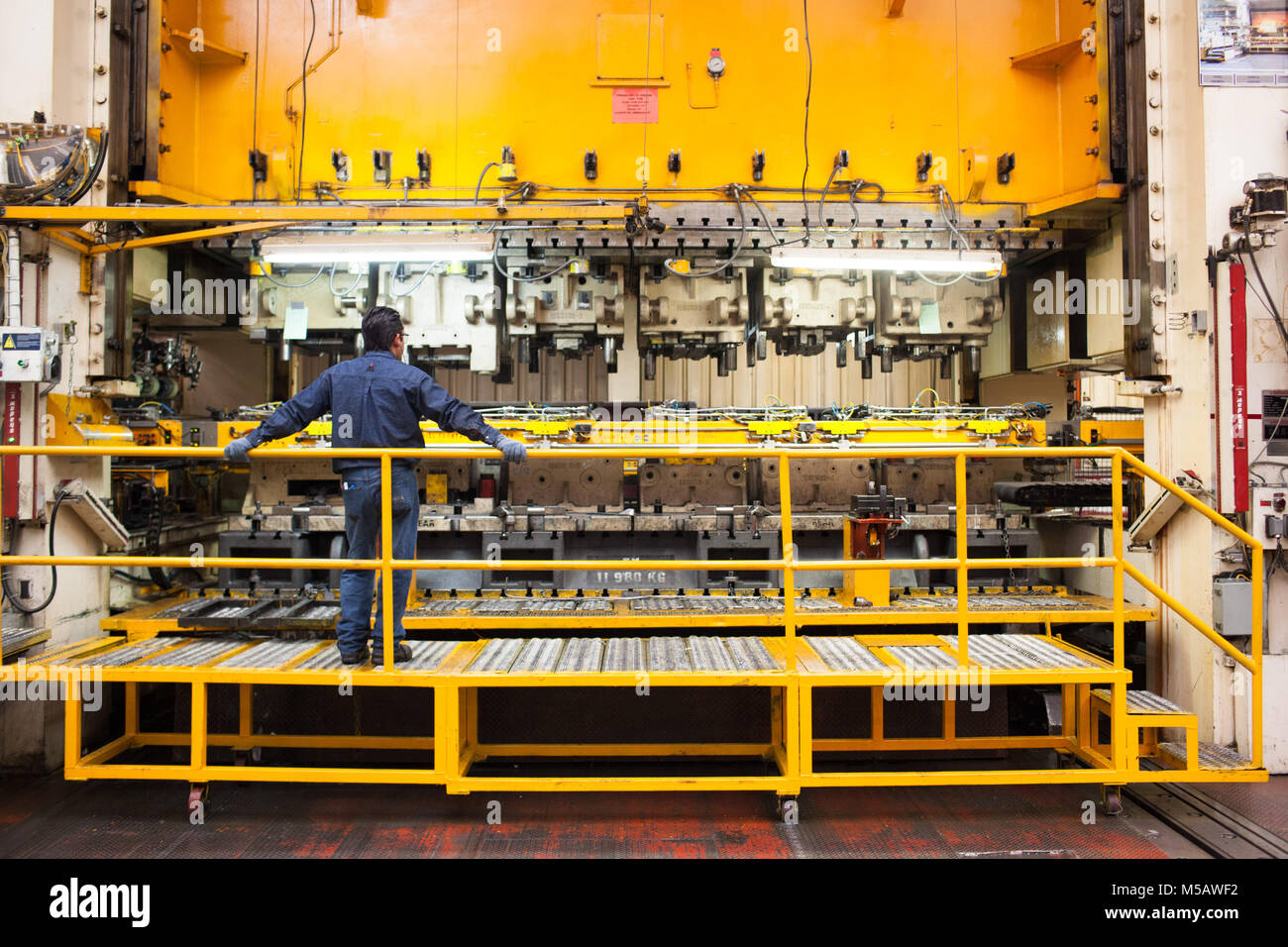 A worker watches a press machine at the Magna plant in Puebla, Mexico