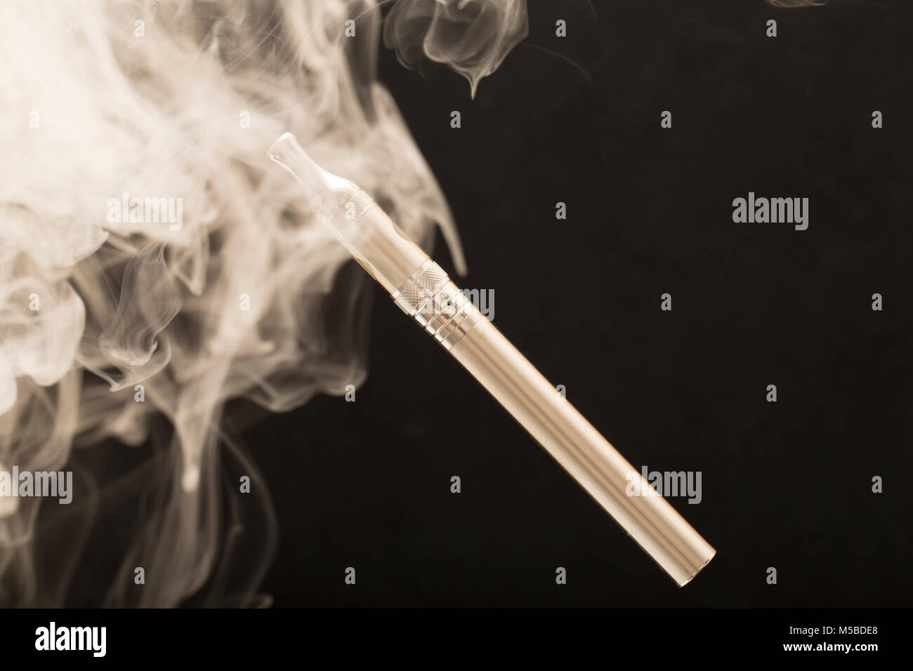 Electric cigarette or E cigarette surrounded by vapour from its E liquid. England UK GB. Photographed on a black background. Stock Photo