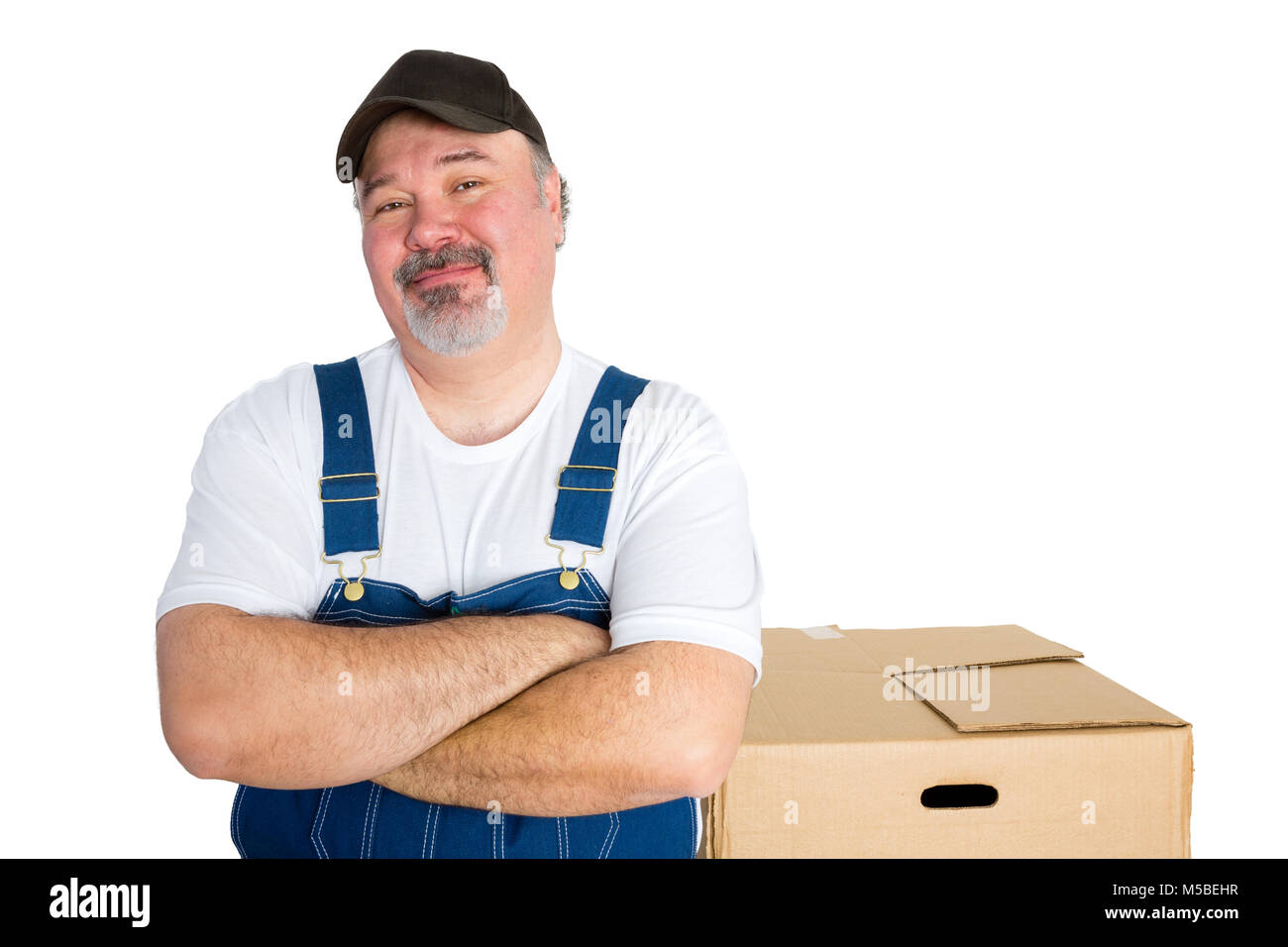 Cheerful delivery man standing against big cardboard box Stock Photo