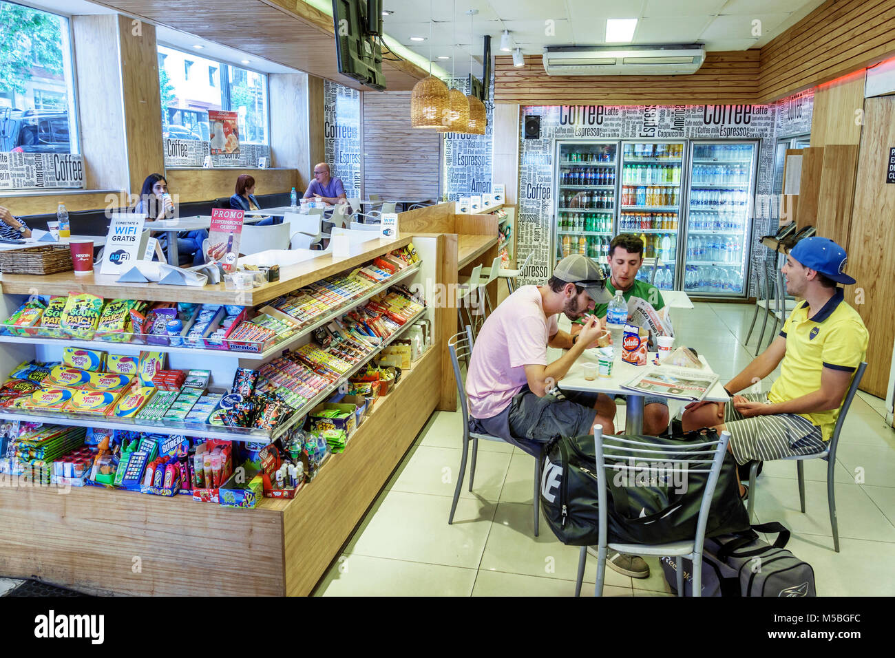 Buenos Aires Argentina,convenience store,cafe,sundries,snacks,Hispanic Latin Latino ethnic minority,adult adults man men male,sitting seated,eating,vi Stock Photo