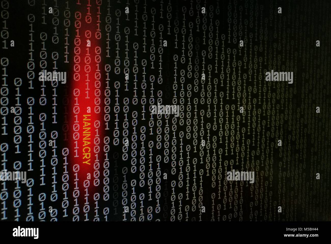 computer virus. binary data shown on black screen with wannacry text hilight with red colour. Stock Photo