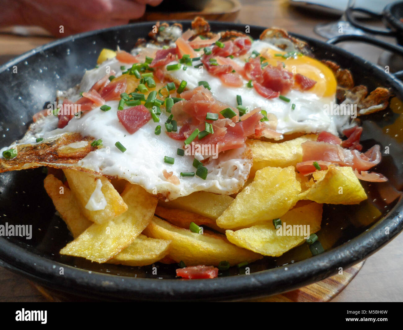 Fried egg on a bed of deep fried potato chips hires stock photography