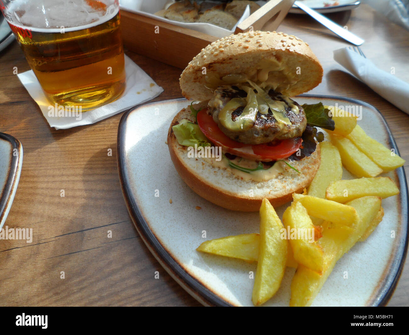 Hamburger a seeded bread with a side of potato chips/fries served in a Spanish Tapas bar, Fuengirola, Stock Photo - Alamy