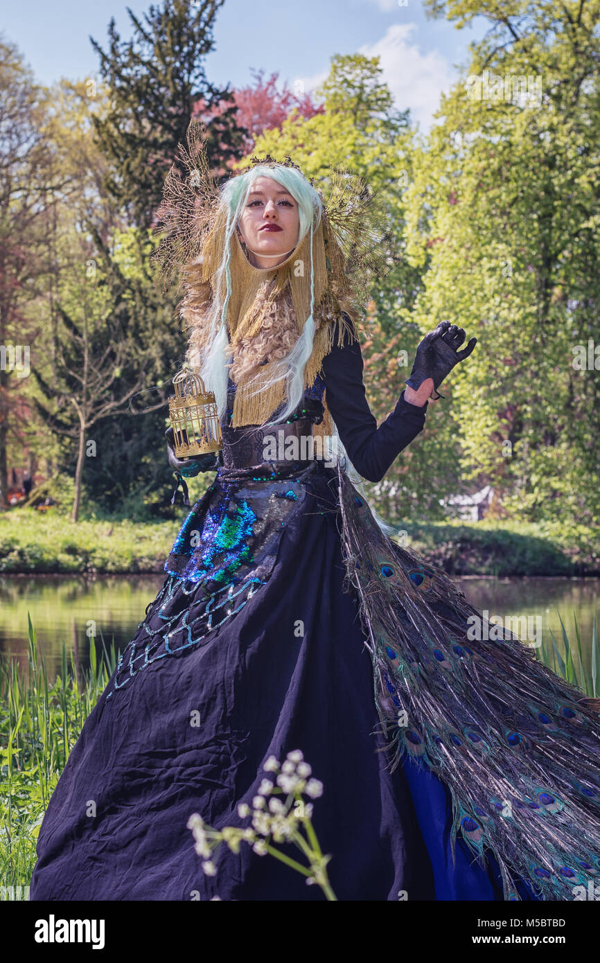 April  19, 2014, Haarzuilens, The Netherlands: Beautiful woman dressed in a peacock dress poses in the park during the Elf Fantasy Fair (Elfia) is an  Stock Photo