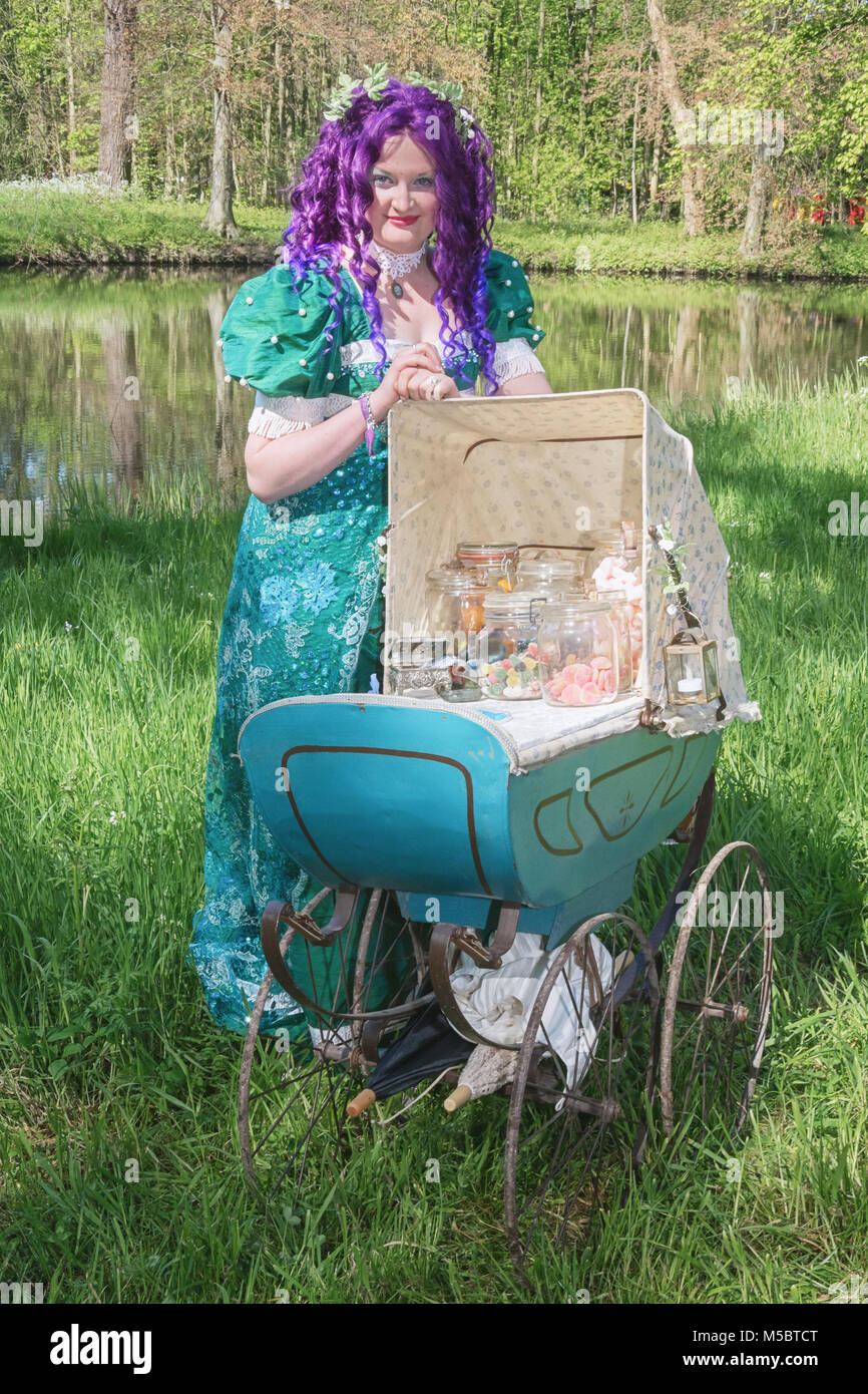 April  19, 2014, Haarzuilens, The Netherlands: Dressed woman with a purple wig and antique pram filled with glass jars with candy during the Elf Fanta Stock Photo