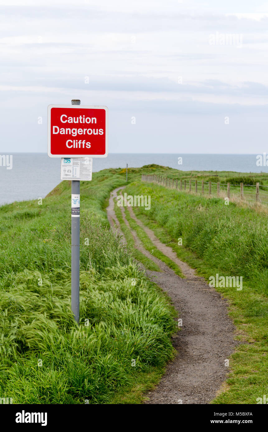 'Caution Dangerous Cliffs' Warning Sign on the Clifftop at Collywell Bay, Seaton Sluice, Northumberland Stock Photo