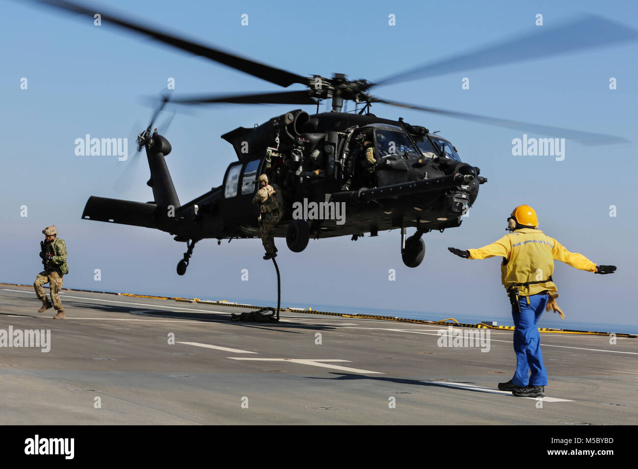 U.S. 5TH FLEET AREA OF OPERATIONS (Feb. 6, 2018) U.S. military forces fast rope out of an U.S. Army UH-60 Black Hawk onto the deck of French amphibious assault ship LHD Tonnerre (L9014) during a bilateral training evolution. The Tonnerre, with embarked Marines and Sailors from Naval Amphibious Force, Task Force 51/5th Marine Expeditionary Brigade and US Special Operations Forces are conducting maritime security operations within the U.S. 5th Fleet area of operations to ensure regional stability, freedom of navigation and the free flow of commerce with regional partners. (U.S. Marine Corps phot Stock Photo