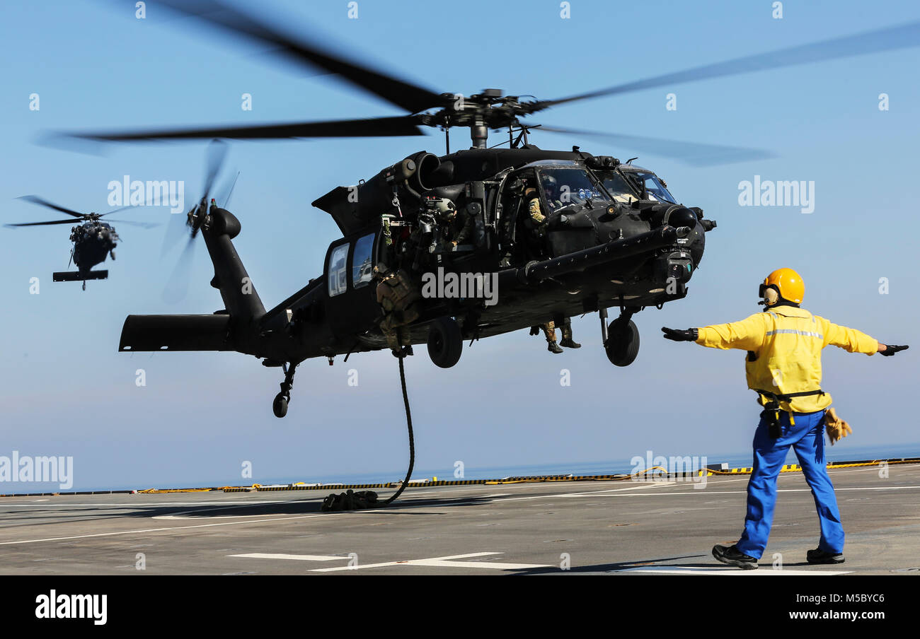 U.S. 5TH FLEET AREA OF OPERATIONS (Feb. 6, 2018) U.S. military forces fast rope out of an U.S. Army UH-60 Black Hawk onto the deck of French amphibious assault ship LHD Tonnerre (L9014) during a bilateral training evolution.  The Tonnerre, with embarked Marines and Sailors from Naval Amphibious Force, Task Force 51/5th Marine Expeditionary Brigade and US Special Operations Forces are conducting maritime security operations within the U.S. 5th Fleet area of operations to ensure regional stability, freedom of navigation and the free flow of commerce with regional partners. (U.S. Marine Corps pho Stock Photo