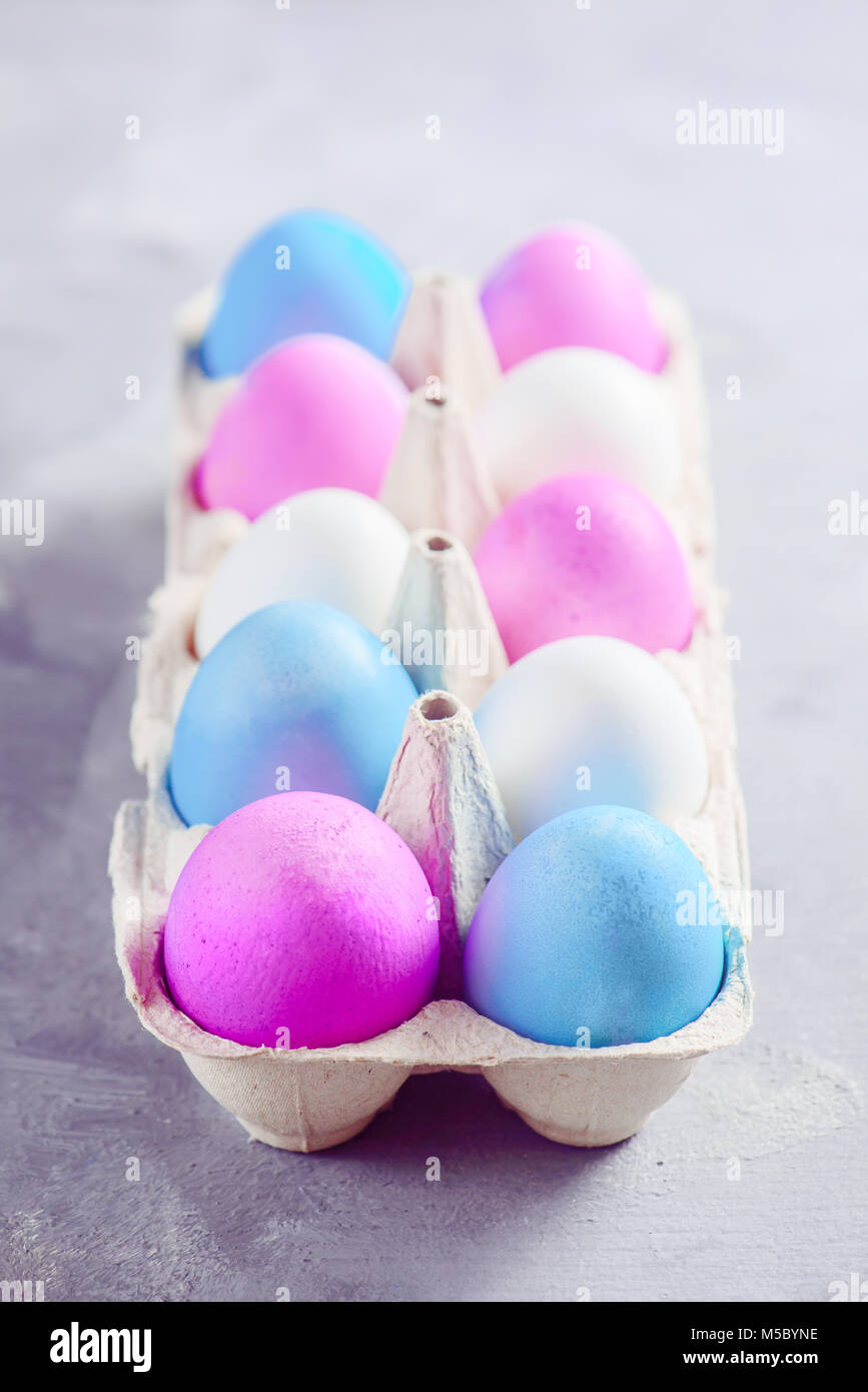 Carton with Easter eggs painted in shades of blue, pink and purple. Modern concept with copy space. Stock Photo