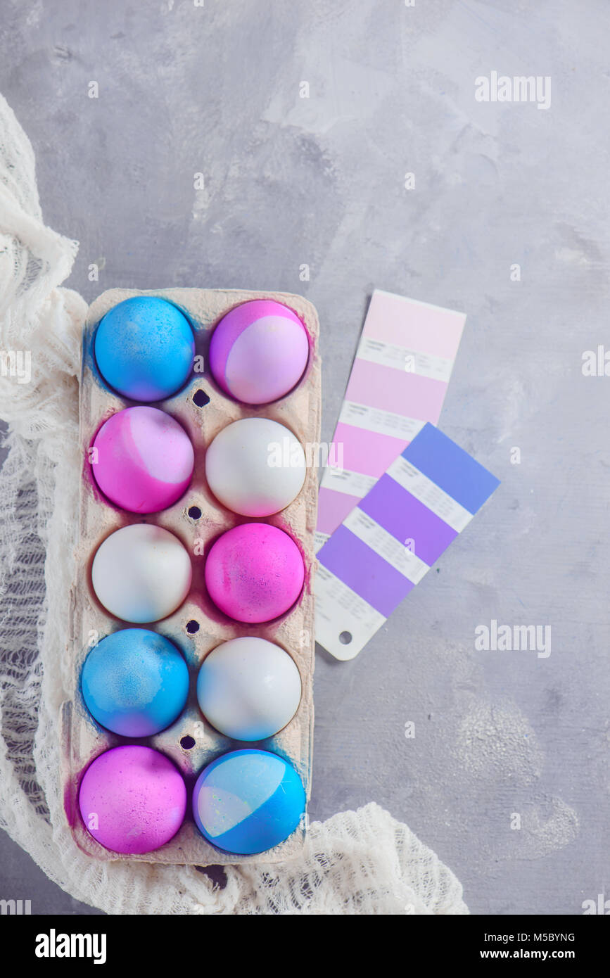 Easter eggs painted in blue and pink shades in a carton with color swatches. Preparing for holidays. Minimalist Easter decorations with copy space. Stock Photo