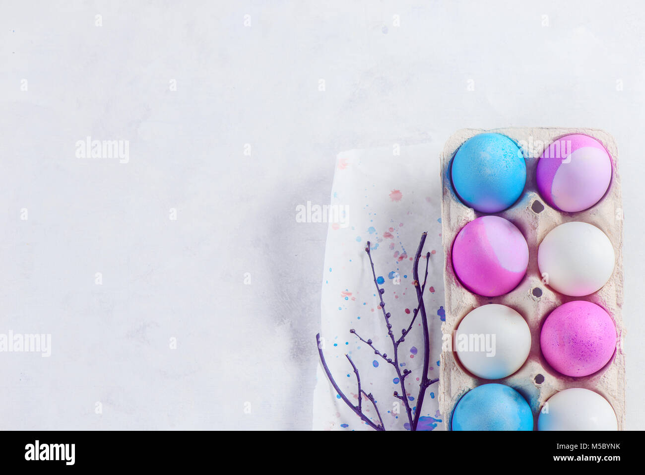 Easter eggs painted in blue and purple shades in a carton with tree ...