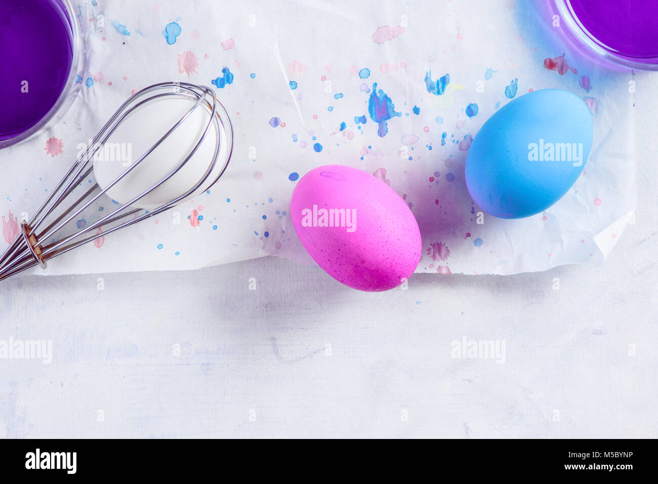 Easy way to paint Easter eggs. Using a whisk and food dye. Minimalist Easter decorations from above. Copy space. Stock Photo