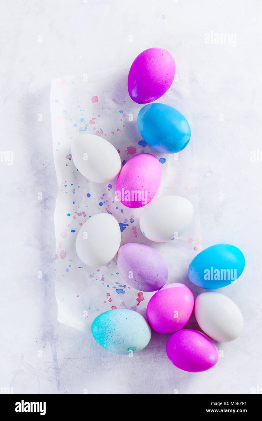 An assortment of Easter eggs on a light background. High key holiday concept from above. Shades of blue, pink and purple. Stock Photo