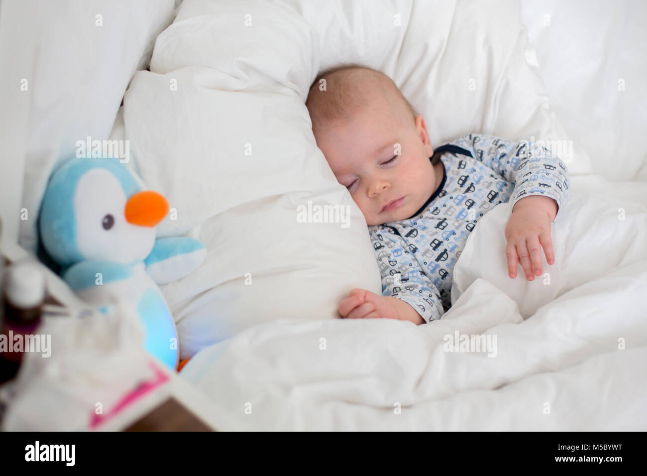 Sick chidl, bab boy lying in bed with a fever, resting at home Stock