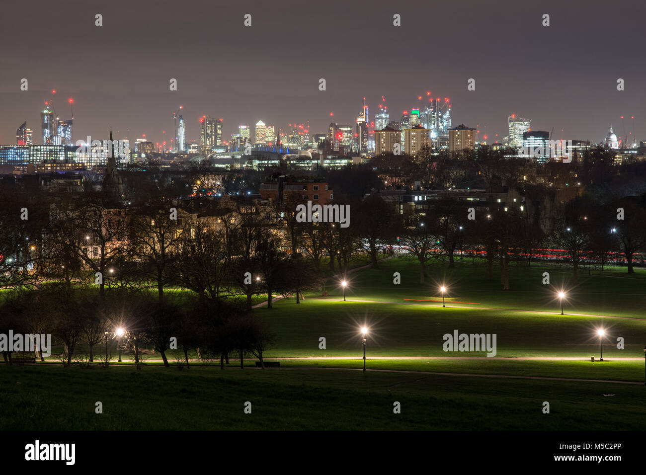 London, England, UK - February 2, 2018: Skyscrapers and landmarks in the London skyline are lit up at night as viewed from Primrose Hill, with Regent' Stock Photo