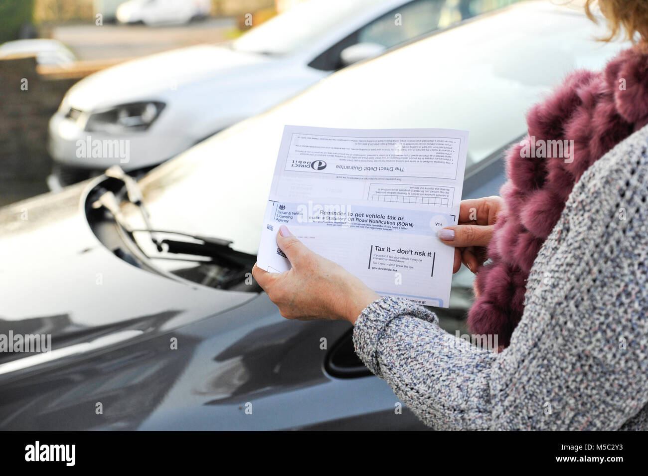 Woman checking her DVLA car vehicle Tax Renewal reminder notice Stock Photo