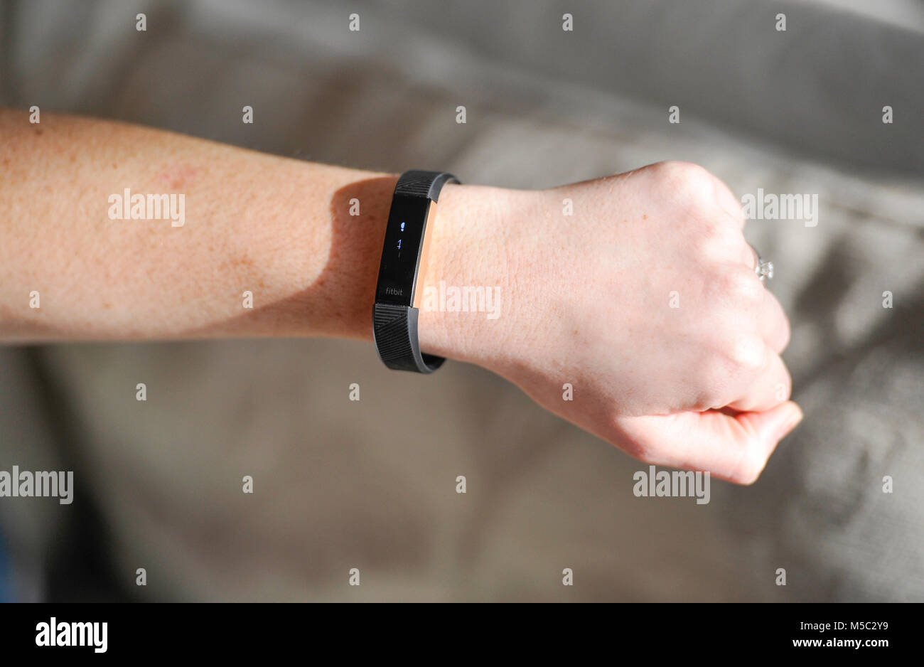 Young woman wearing a Fitbit watch Photograph taken by Simon Dack Stock Photo