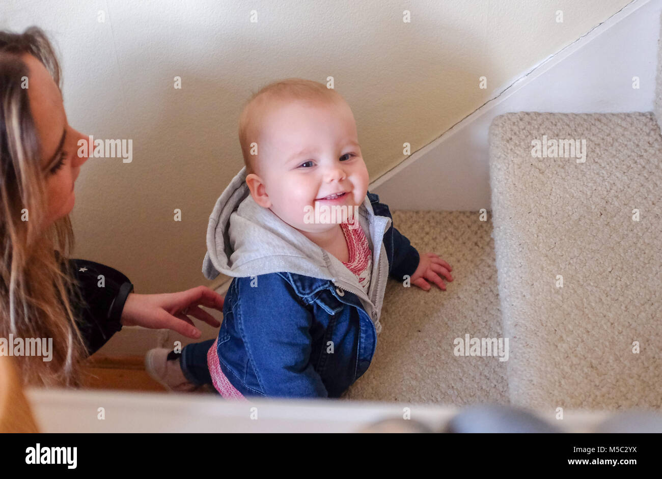 Cute female baby toddler at home learning to go up the stairs Stock Photo