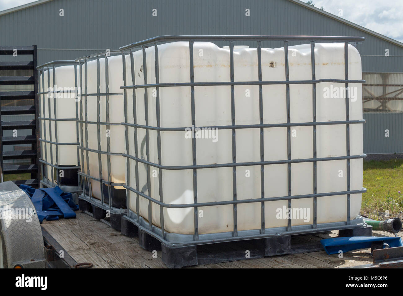 Three water containers on a flat bed trailer on a farm for watering