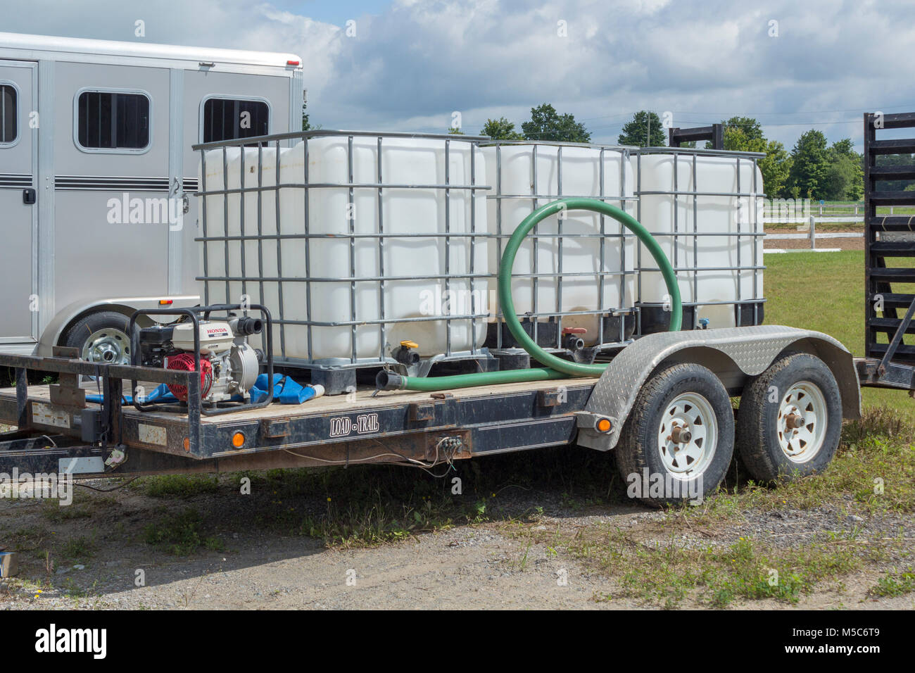 Three water containers ona flatbed trailer with generator for watering