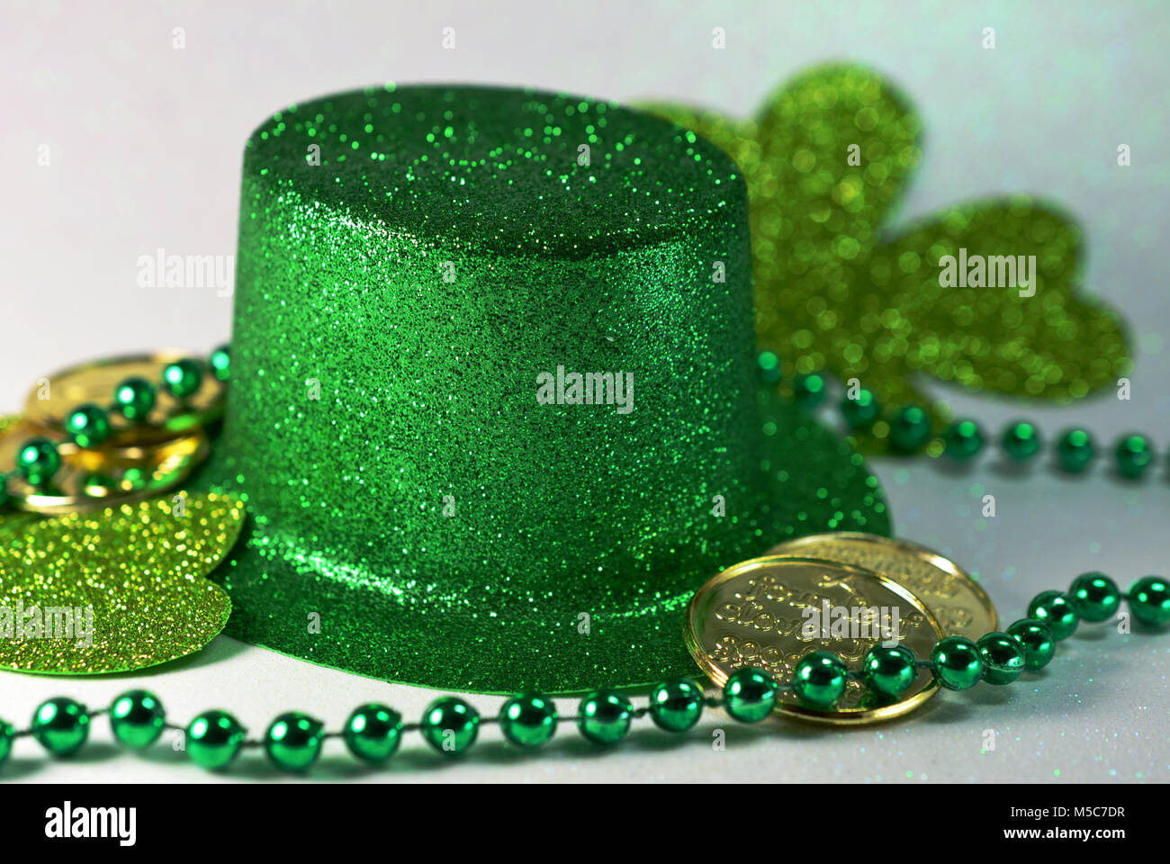 St Patricks Day Green Top hat, green beads, golf four leaf clover and gold coins. Stock Photo