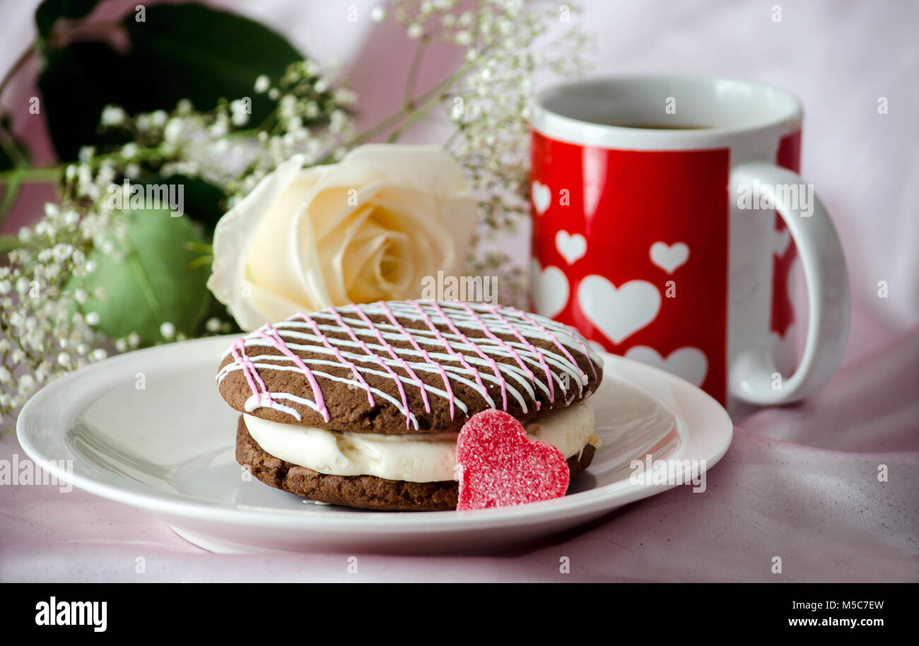 pink and white decorated whoopie Cake and heart mug with a rose, a delicious still life for valentines day Stock Photo