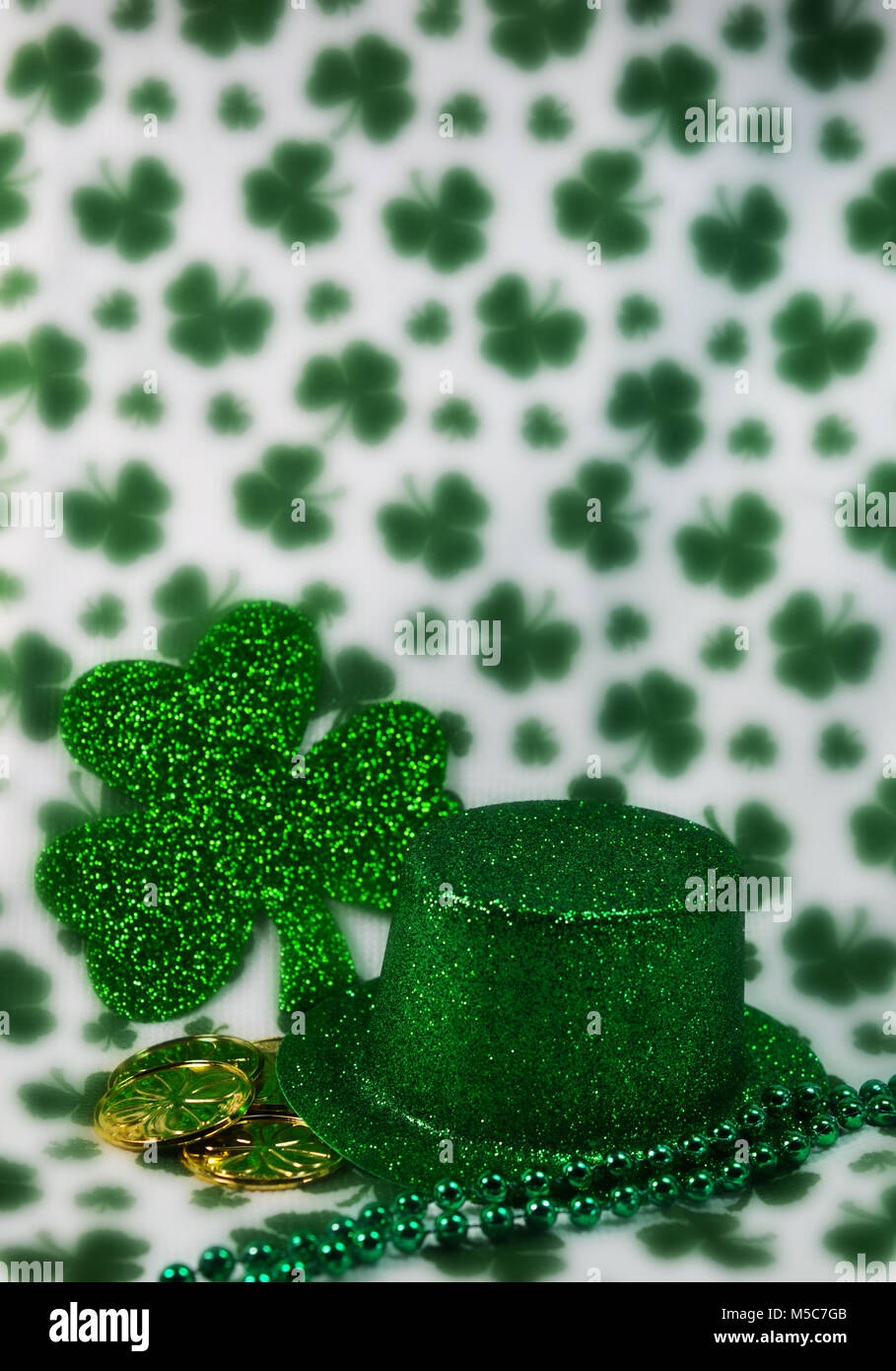 Irish Glittery Green Top Hat with Shiny Green Four Leaf Clover shamrock background and gold coins Stock Photo