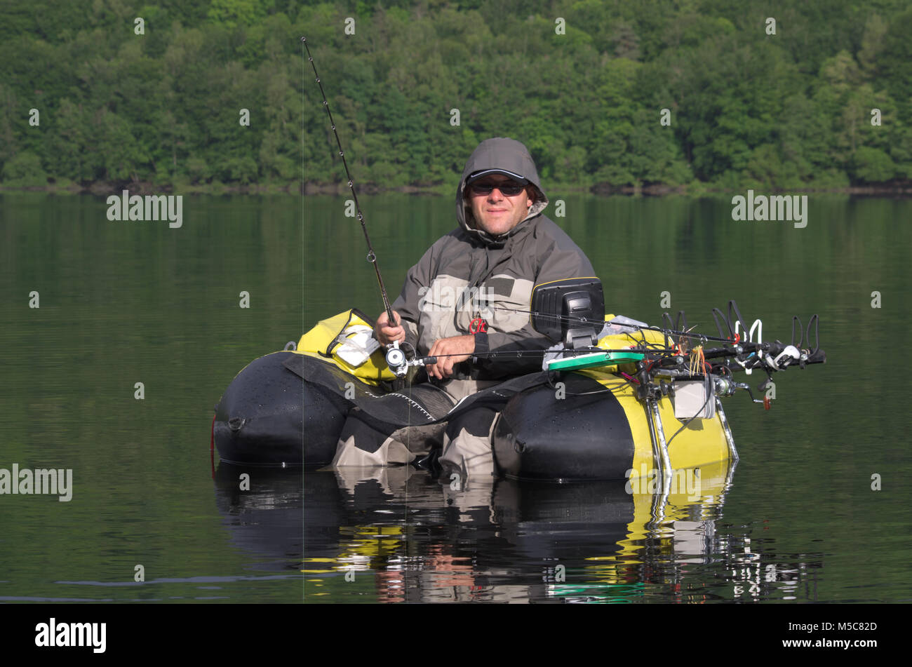 Fishing with a float tube. The man is sitting in the fishing inflatable boat  and he use flippers to move on the water Stock Photo - Alamy